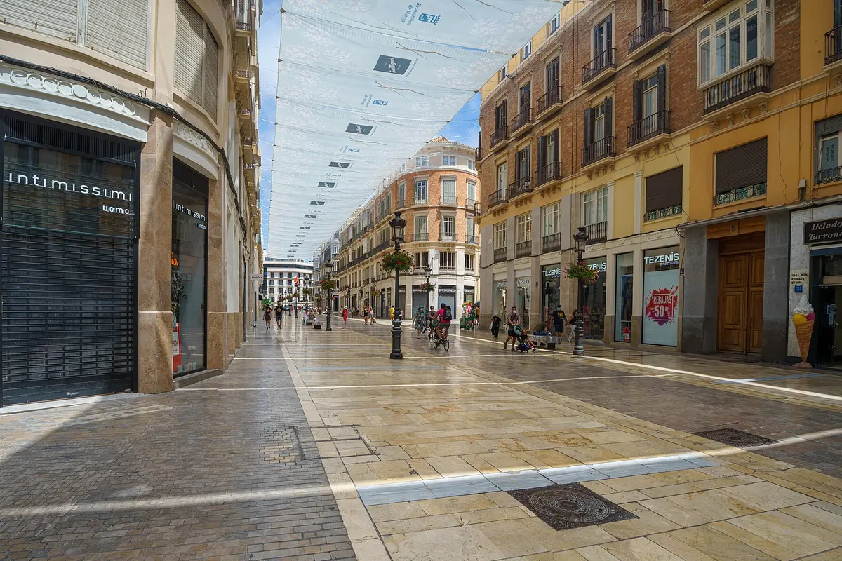Calle Marqués de Larios in Málaga, a wide pedestrian street of stone paving and tall painted buildings, with awnings stretched overhead